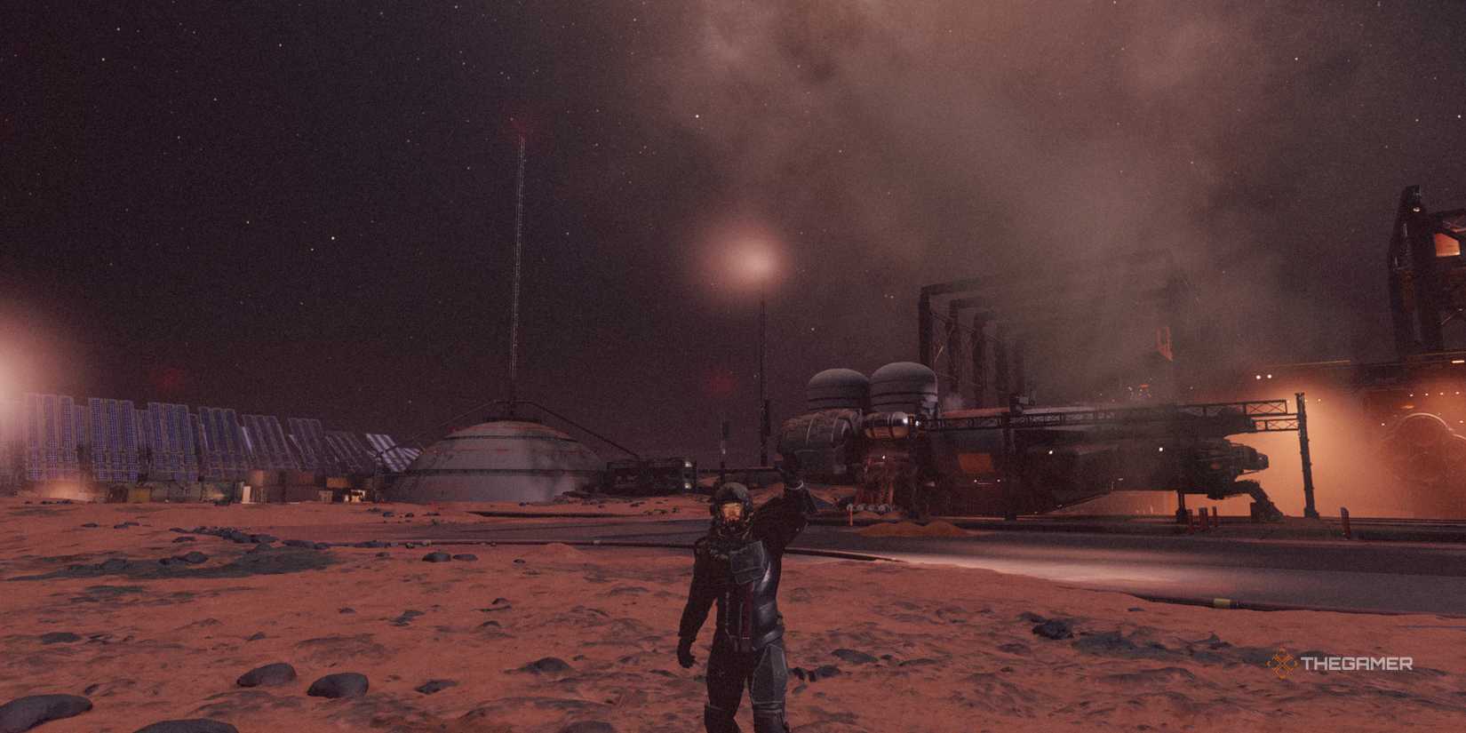 The player waving while standing outside on Mars by some shipyards in Starfield.